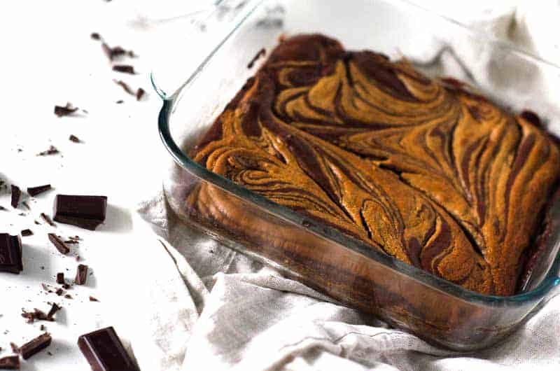 uncut brownies in pan surrounded by chocolate