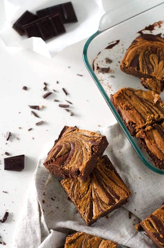 Gluten free dairy free brownies on table with flakes of chocolate and pan in background