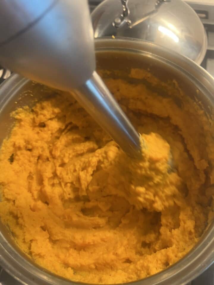 mashed sweet potatoes being blended with immersion blender