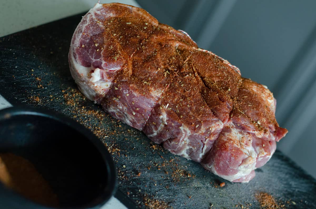 Pork butt on cutting board with dry rub on it