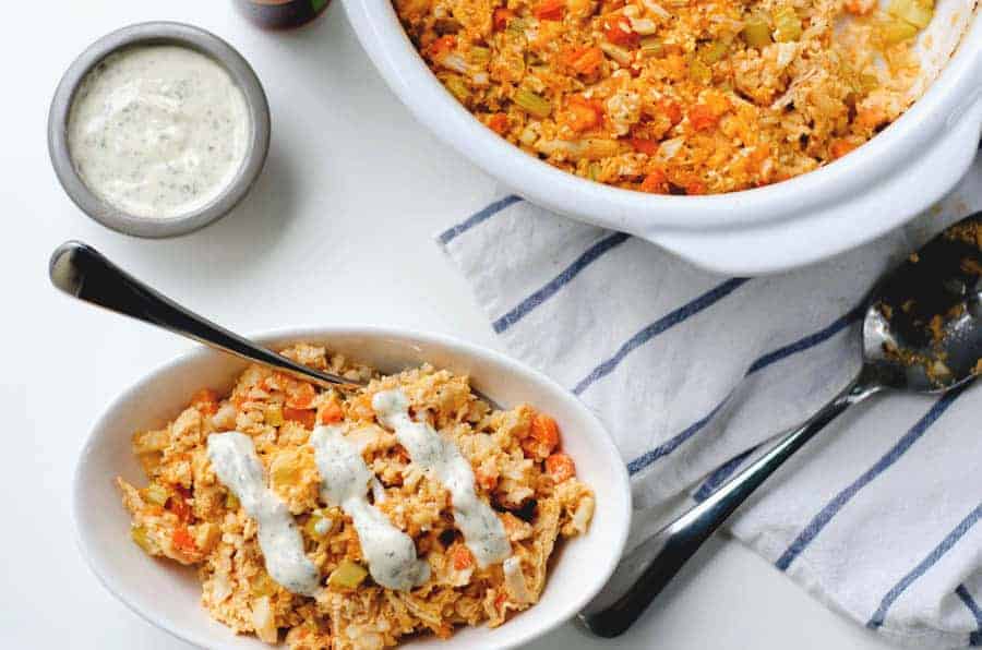 overhead view of paleo buffalo chicken casserole in a casserole dish with ranch nearby