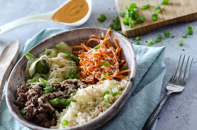 View of table with korean ground beef bulgogi bowl surrounded by kitchen tools and ingredients