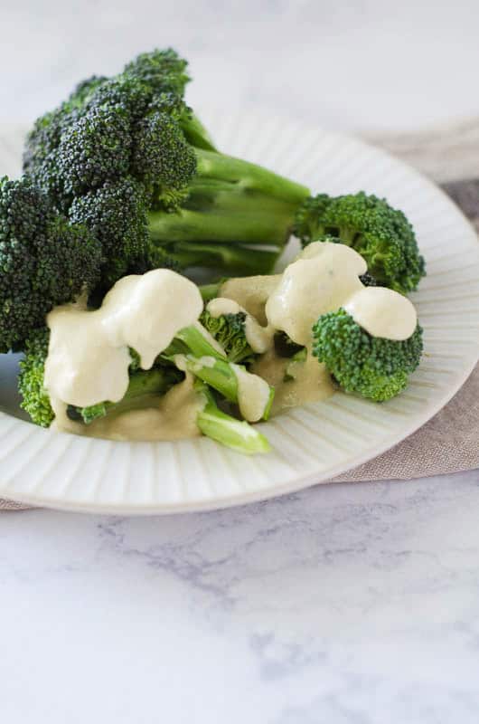 broccoli florets on a plate with dairy free cheese sauce