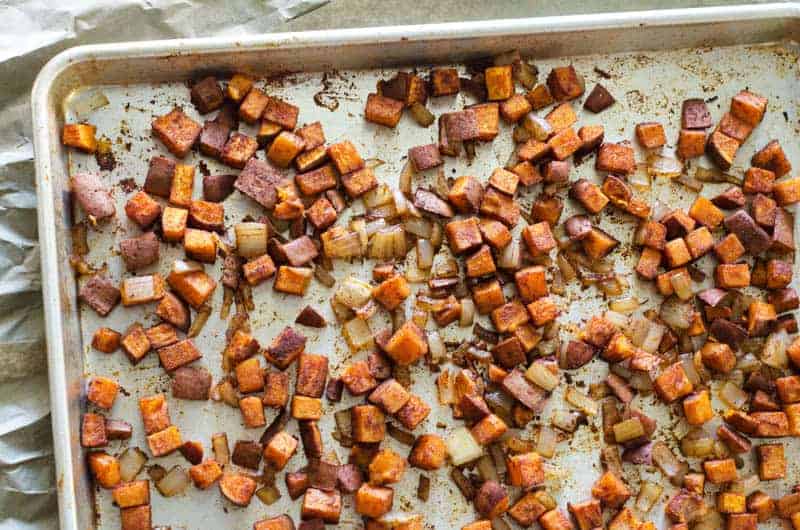 Overhead view of a baking sheet with cinnamon roasted sweet potatoes and onions