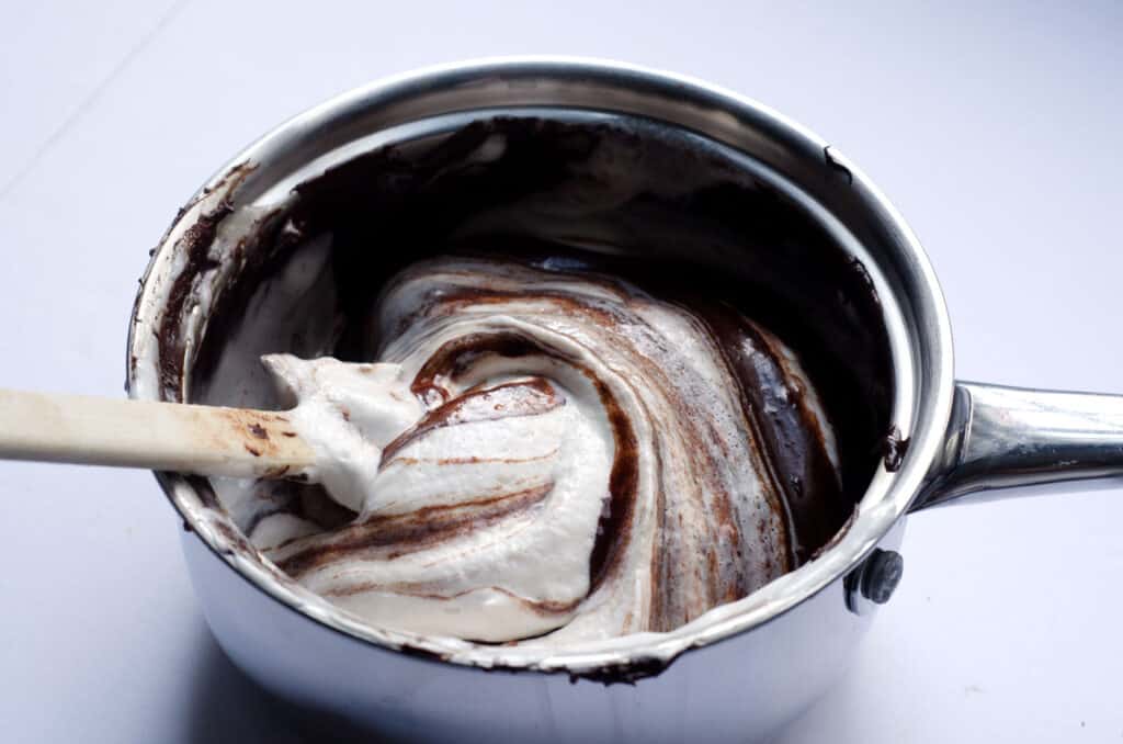 pot of melted chocolate getting coconut whipped cream folded in