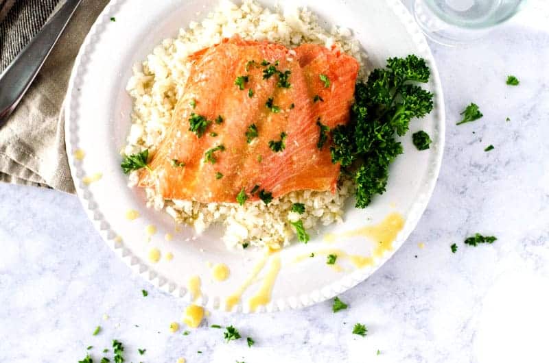 Citrus glazed whole30 salmon over cauliflower rice on a white plate