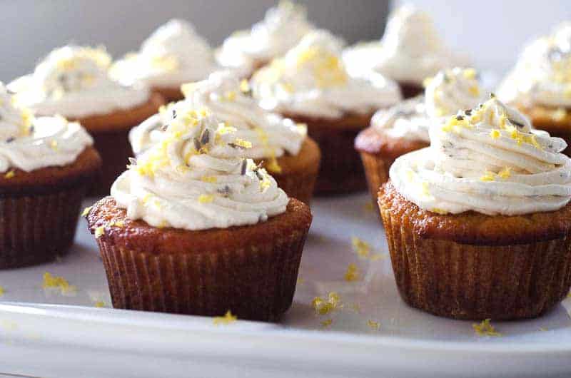 side view of lemon cupcakes on a tray topped with lemon lavender icing