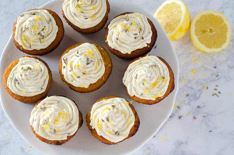 Overhead view of lemon lavender cupcakes on a cake stand with a lemon in the background