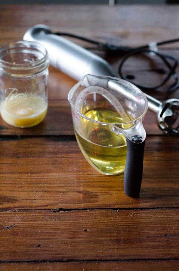 mason jar with egg, measuring cup with oil, and immersion blender all on table to make paleo mayo