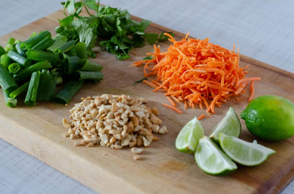 cutting board with gluten free pad thai ingredients prepped