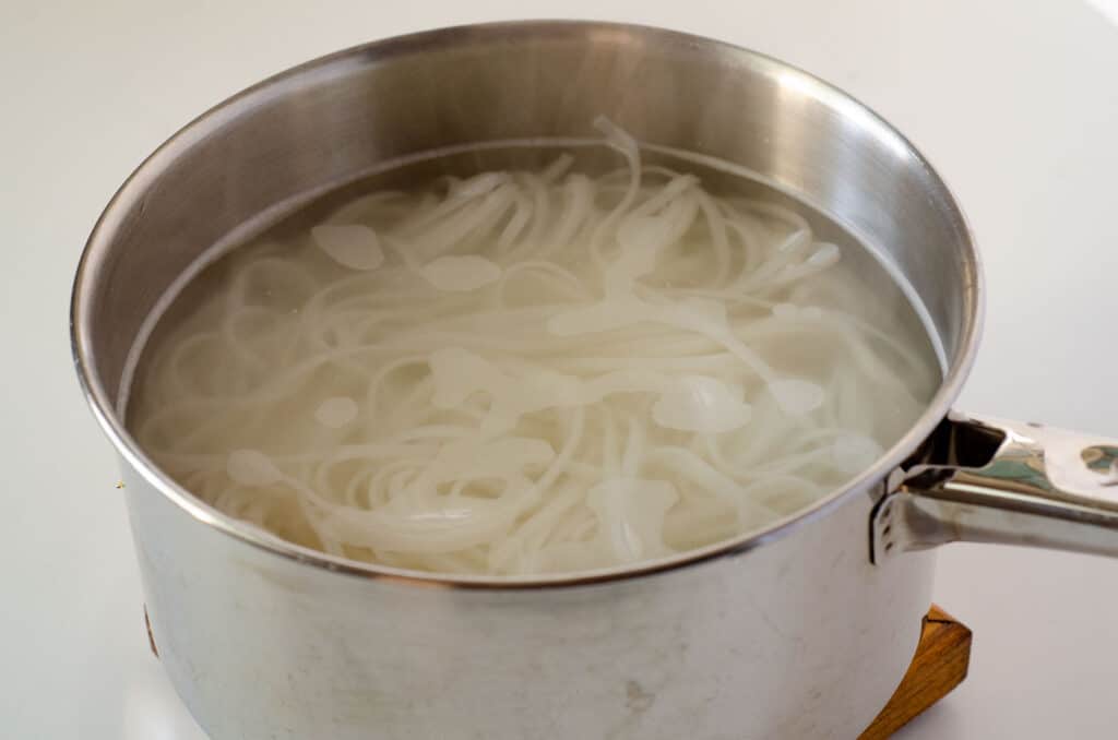 Pot cooking gluten free pad thai rice noodles in water