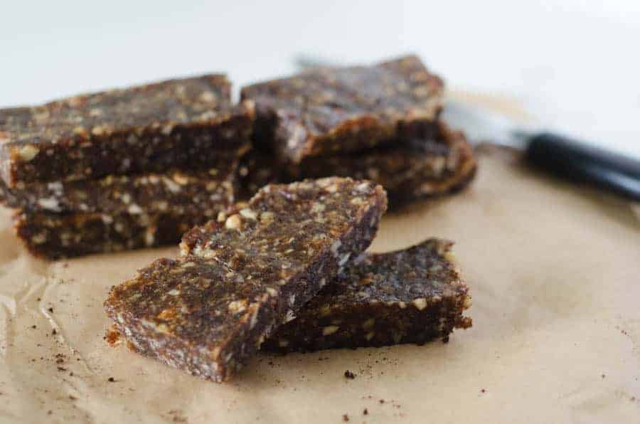 side view of homemade date bars stacked on butcher paper with a knife in the background