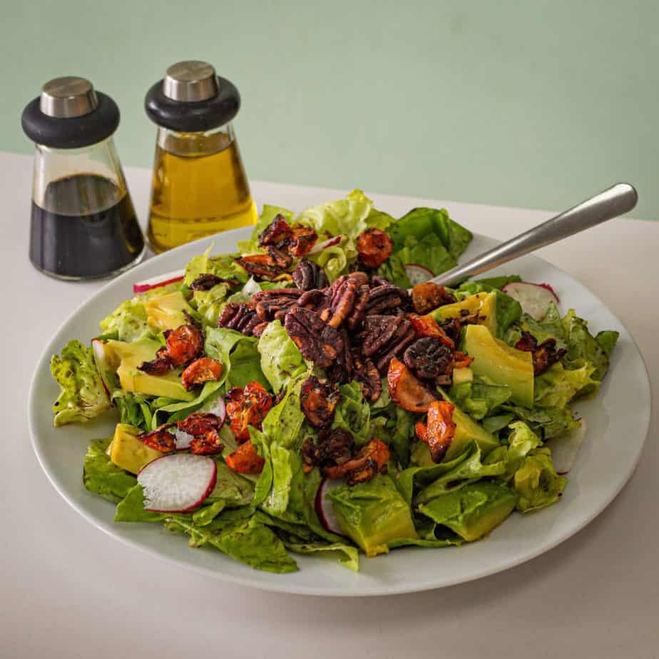 simple salad with oil and vinegar dressing next to it