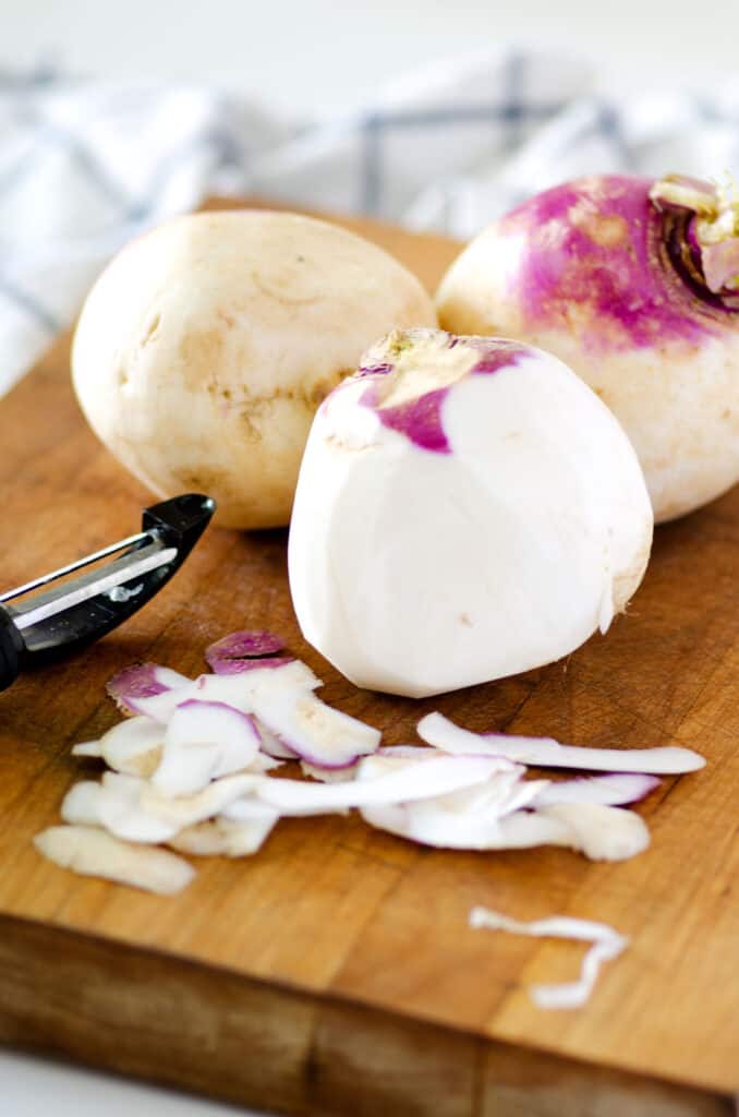 turnips on a cutting board with peeler 