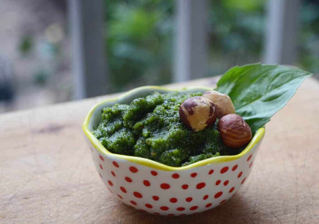 Dairy free pesto in a polka dot bowl topped with hazelnuts and fresh basil