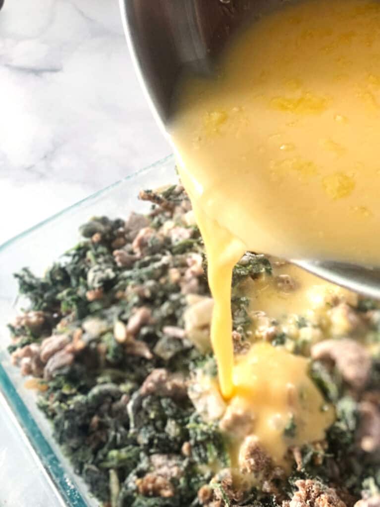 Close up shot of eggs being poured into pan of spinach egg casserole