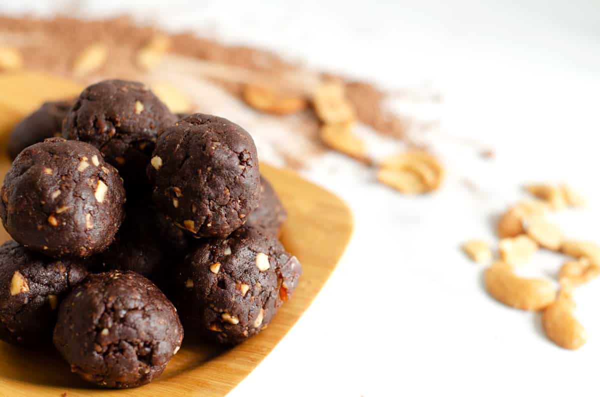 Side view of chocolate paleo protein balls on a bamboo plate