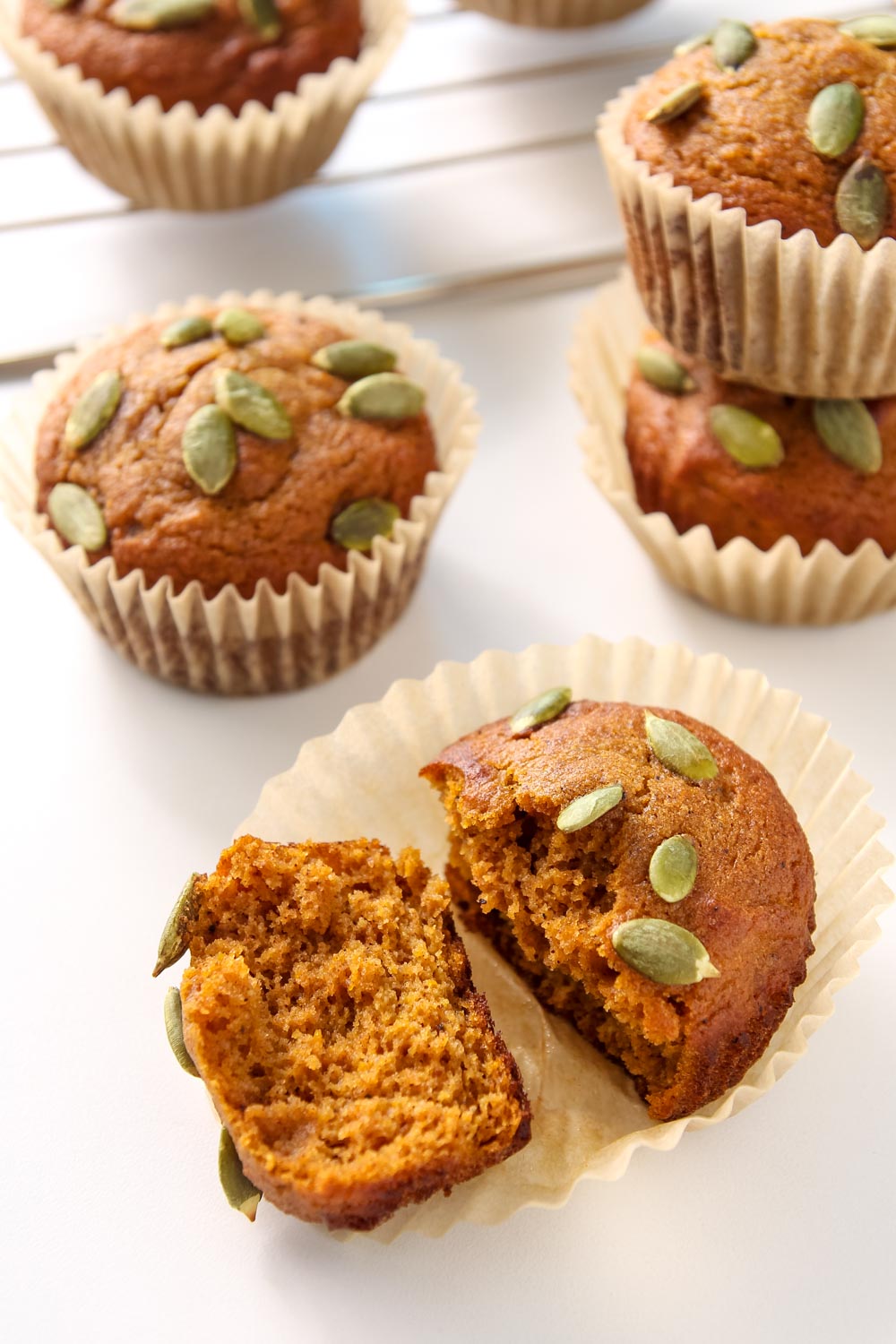 Overhead view of pumpkin muffin torn in half on muffin wrapper. 