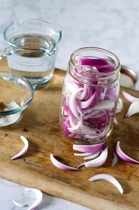 Side overhead view of a mason jar packed with red onion slices