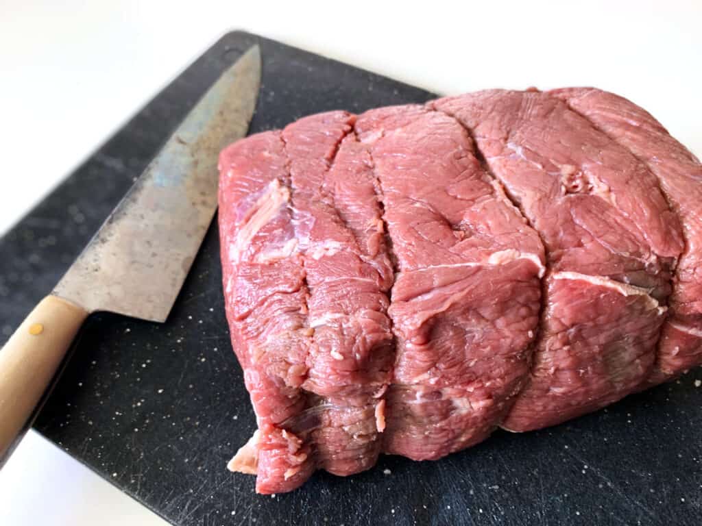 large chuck roast on a cutting board with knife in the background