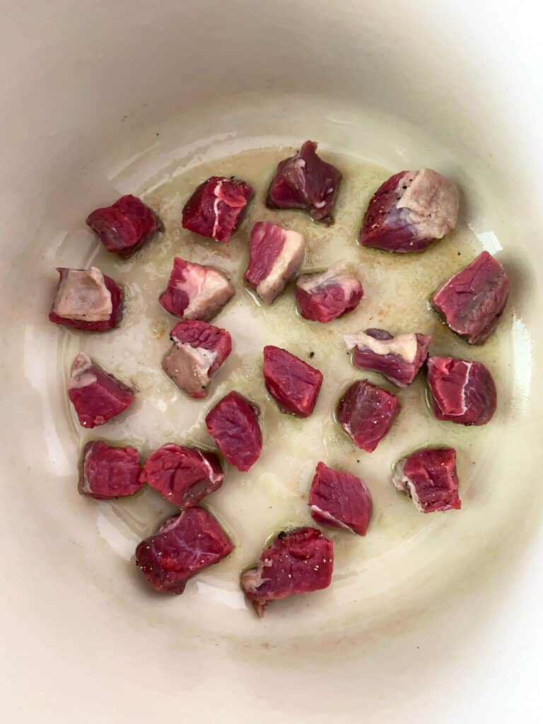 chunks of chuck roast browning in a dutch oven