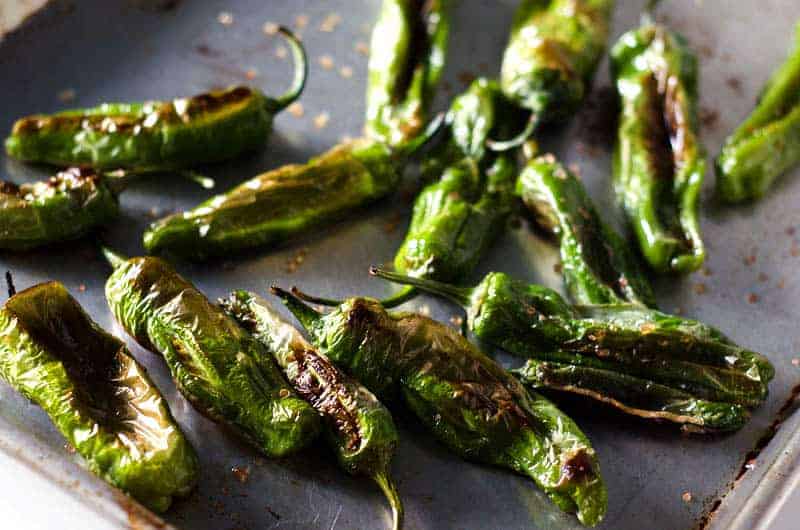 Browned and roasted shishito peppers on baking sheet