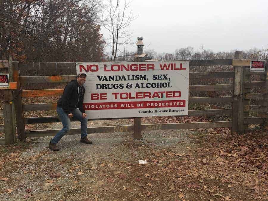 Man standing next to sign on fence