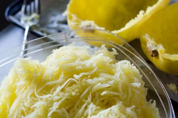 Tupperware with spaghetti squash in it with skins in the background