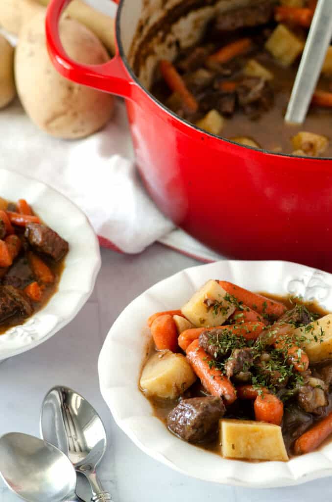 bowls of paleo beef stew with spoons in foreground and dutch oven in background