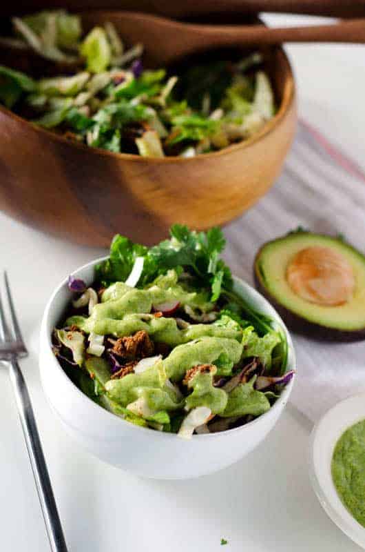 White serving bowl of Whole30 taco salad topped with avocado dressing