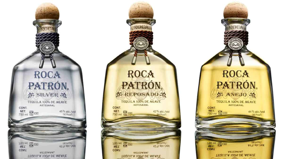 Three bottles of tequila in a row showing the colors of blanco, reposado, and añejo tequilas