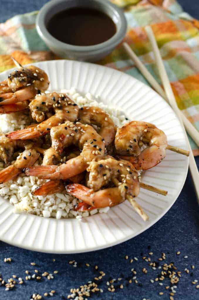 Close up of ginger teriyaki Traeger shrimp on a plate with cauliflower rice and dipping sauce