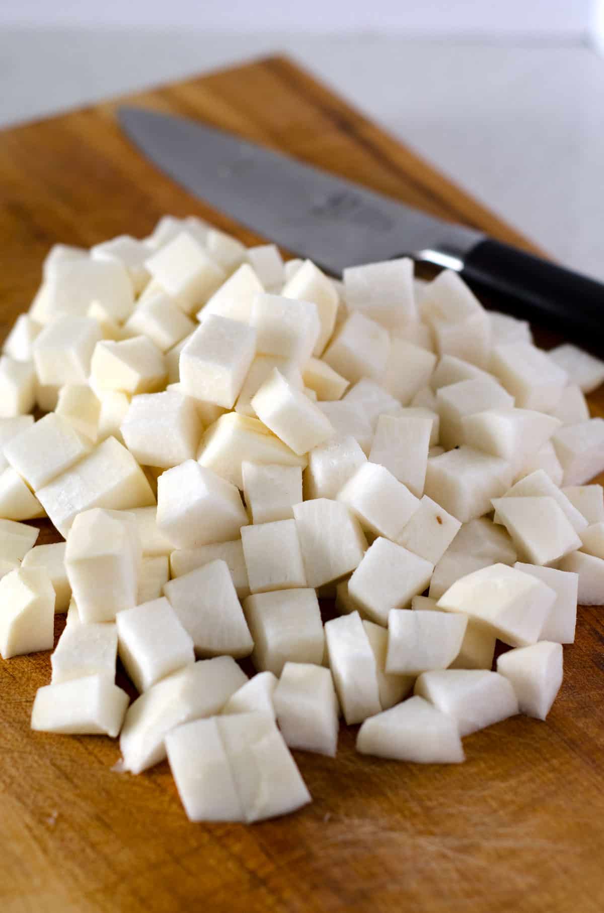 cubed turnips on cutting board with knife in the background