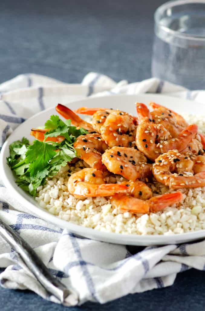 Close up of Whole30 shrimp on a plate of cauliflower rice topped with sesame seeds